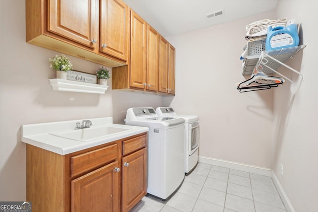 washroom featuring washing machine and clothes dryer, light tile patterned floors, cabinet space, visible vents, and a sink