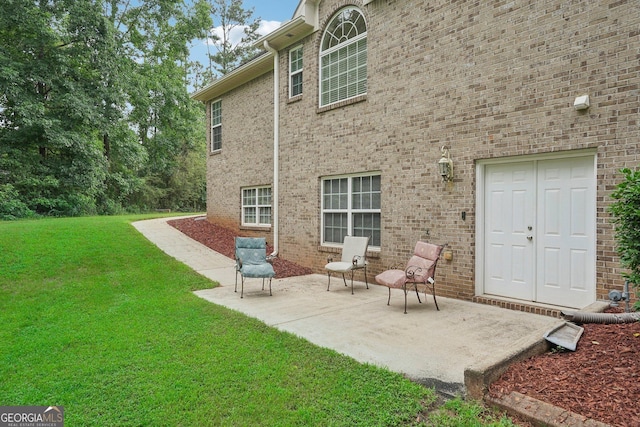 back of property featuring a patio area, a lawn, and brick siding