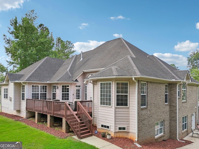 back of house with brick siding, a yard, a shingled roof, a wooden deck, and stairs