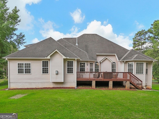 back of property with a wooden deck, a shingled roof, and a yard