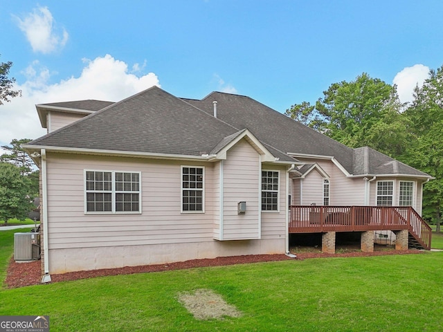 back of property with a yard, a shingled roof, a wooden deck, and central air condition unit