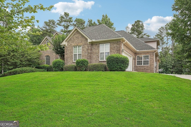 view of front facade with a front lawn, brick siding, a shingled roof, and an attached garage