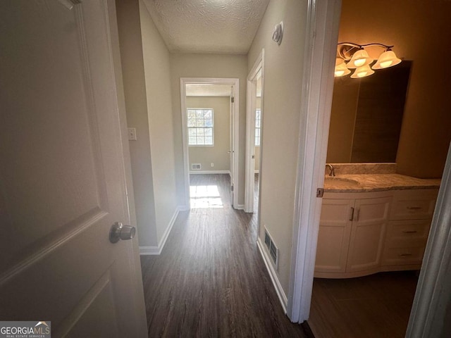 hall with dark hardwood / wood-style flooring and a textured ceiling