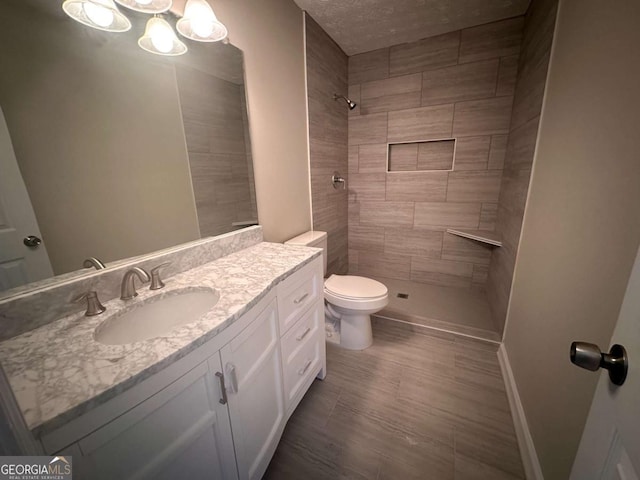 bathroom featuring tiled shower, vanity, and toilet