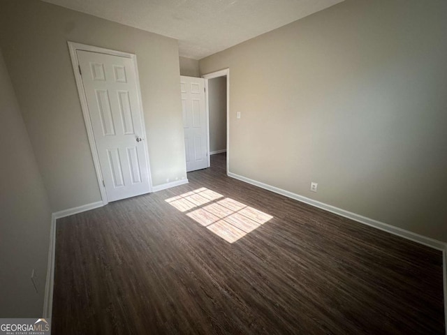 unfurnished bedroom featuring dark hardwood / wood-style flooring and a closet