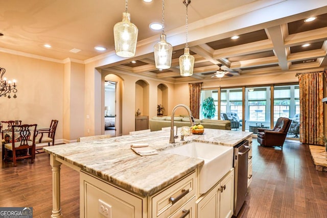 kitchen with coffered ceiling, ceiling fan with notable chandelier, a kitchen island with sink, beam ceiling, and hanging light fixtures