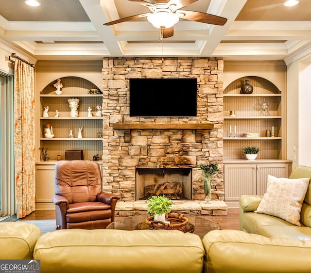 living room featuring hardwood / wood-style flooring, beam ceiling, a stone fireplace, and coffered ceiling