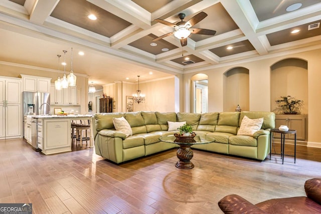 living room with beam ceiling, coffered ceiling, ornamental molding, ceiling fan with notable chandelier, and light wood-type flooring