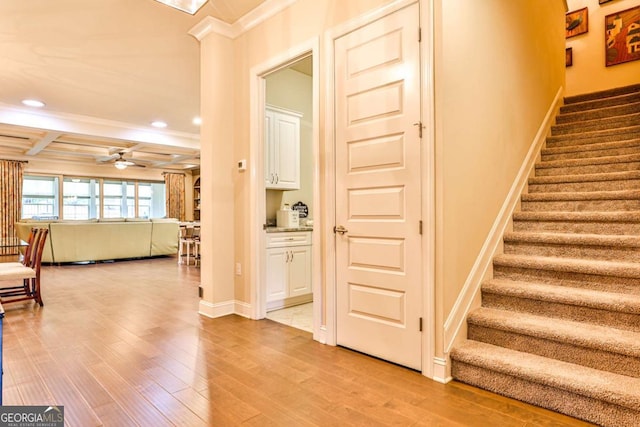 stairway featuring ornamental molding, coffered ceiling, ceiling fan, hardwood / wood-style flooring, and beamed ceiling