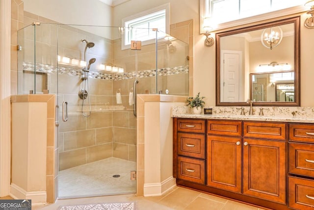 bathroom with tile patterned flooring, vanity, a shower with shower door, and a notable chandelier