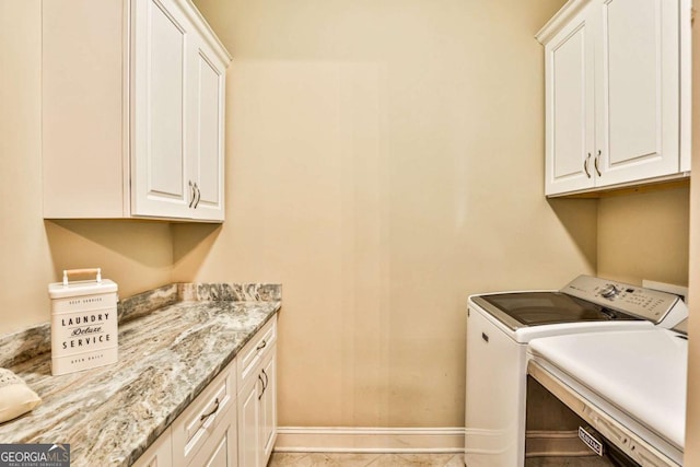 clothes washing area featuring light tile patterned flooring, cabinets, and washing machine and clothes dryer