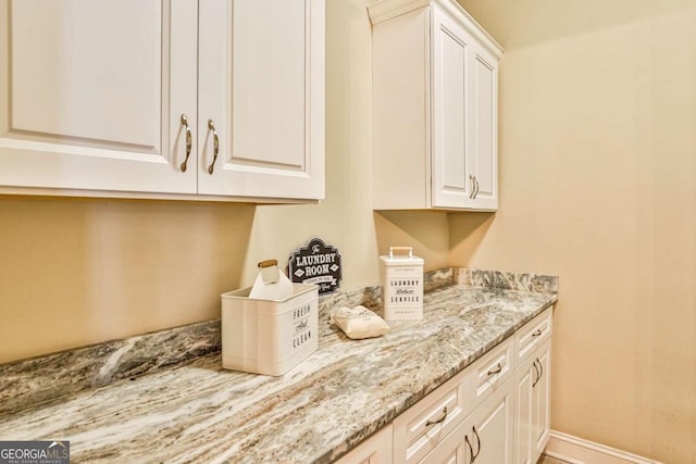 kitchen featuring white cabinetry and light stone countertops