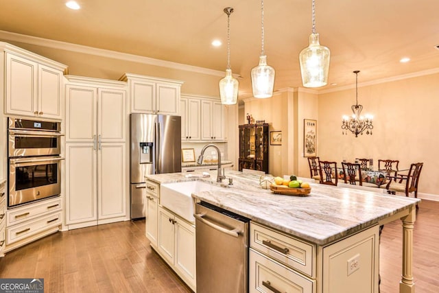 kitchen with a breakfast bar area, sink, a center island with sink, and appliances with stainless steel finishes