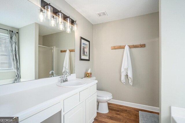 bathroom featuring hardwood / wood-style flooring, toilet, an enclosed shower, and vanity