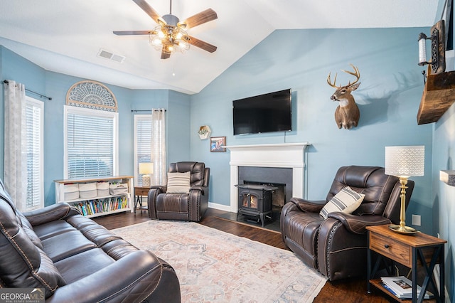 living room featuring a healthy amount of sunlight, dark hardwood / wood-style flooring, vaulted ceiling, and a wood stove