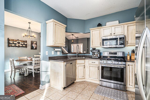 kitchen featuring decorative light fixtures, stainless steel appliances, an inviting chandelier, sink, and light tile patterned floors