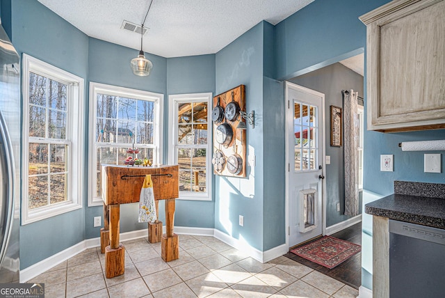 interior space featuring light tile patterned floors, a textured ceiling, light brown cabinetry, and dishwasher