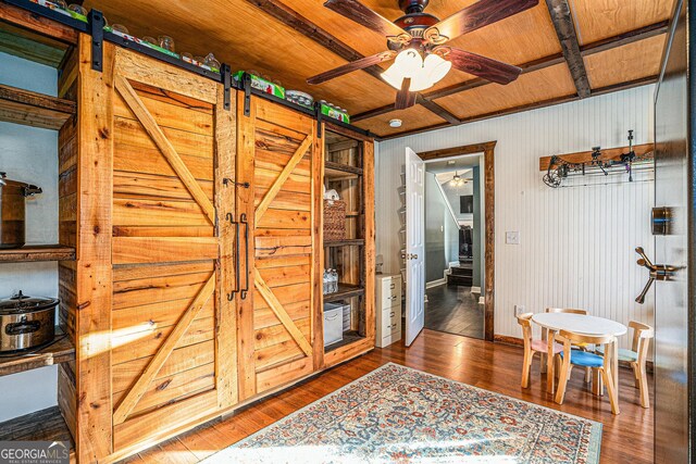 interior space featuring wood ceiling, wood-type flooring, a barn door, and wooden walls