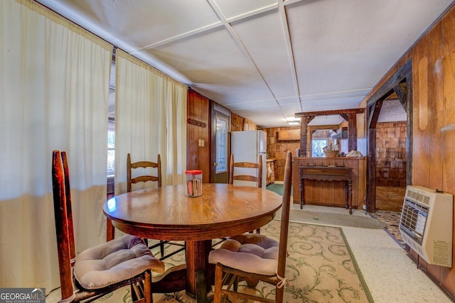 dining area featuring heating unit and wooden walls