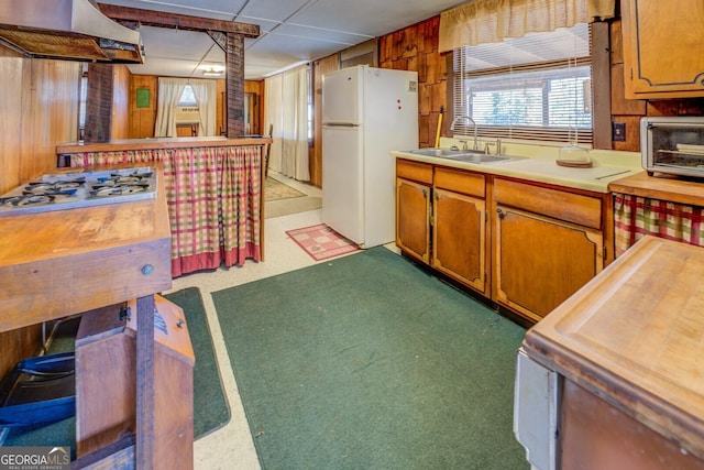 kitchen featuring wood walls, white refrigerator, sink, range hood, and carpet floors