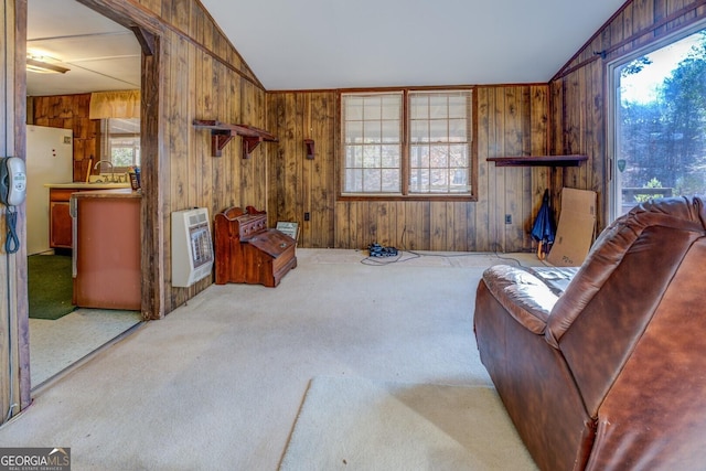 living area with heating unit, light carpet, a healthy amount of sunlight, and lofted ceiling