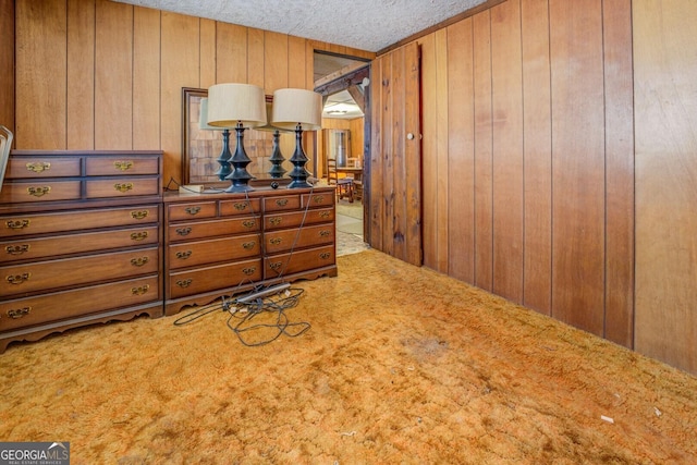 carpeted bedroom featuring wood walls and a textured ceiling