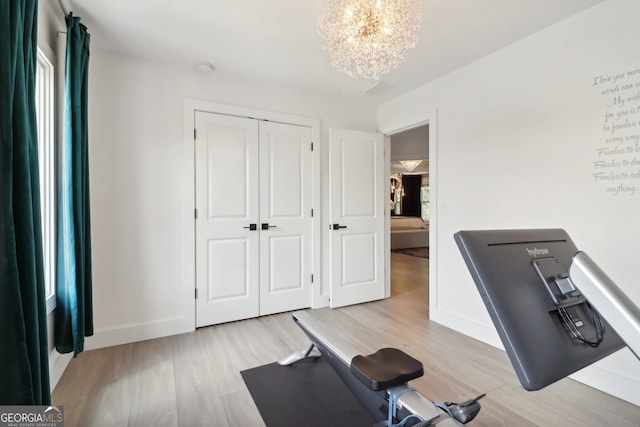 exercise area featuring a notable chandelier and light hardwood / wood-style floors