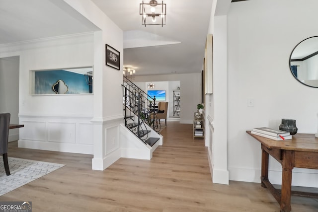 entrance foyer featuring a notable chandelier, light hardwood / wood-style floors, and ornamental molding