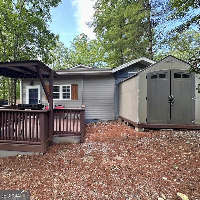 rear view of house featuring a storage shed and a wooden deck