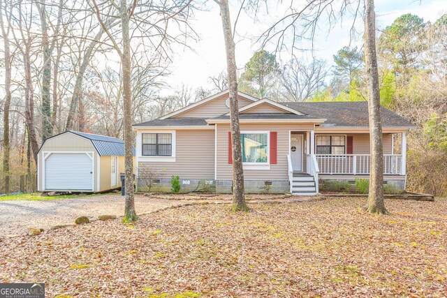 ranch-style house featuring a porch, a garage, and a storage shed