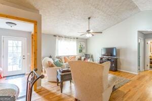 living room featuring vaulted ceiling, light wood-type flooring, a ceiling fan, and baseboards