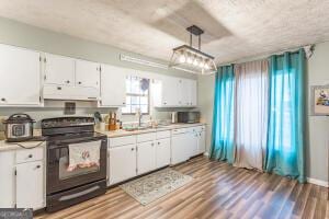 kitchen with pendant lighting, light countertops, white cabinets, and black electric range oven