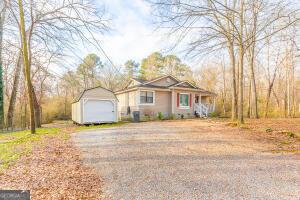 single story home featuring covered porch, a garage, and a storage shed