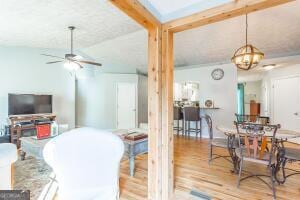 dining space with ceiling fan with notable chandelier, vaulted ceiling with beams, and wood finished floors