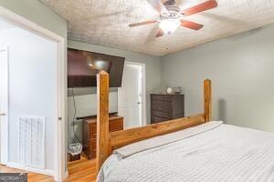 bedroom featuring a ceiling fan, visible vents, and wood finished floors