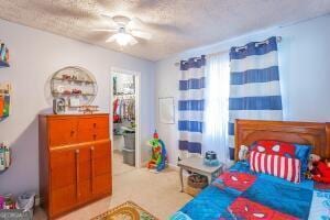 bedroom featuring a ceiling fan, a walk in closet, and a textured ceiling