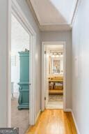 hallway featuring baseboards, wood finished floors, and crown molding