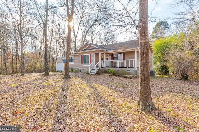 ranch-style house featuring covered porch, a garage, and an outbuilding