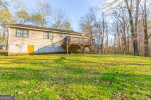 rear view of house featuring a yard, a wooden deck, and stairs