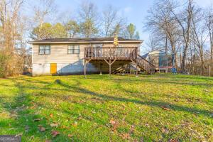 rear view of property featuring stairway, a deck, and a lawn