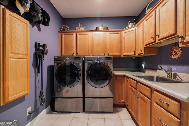 clothes washing area featuring light tile patterned flooring, cabinets, sink, and washing machine and dryer