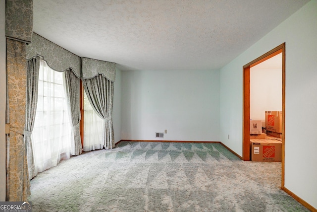 carpeted empty room featuring a textured ceiling