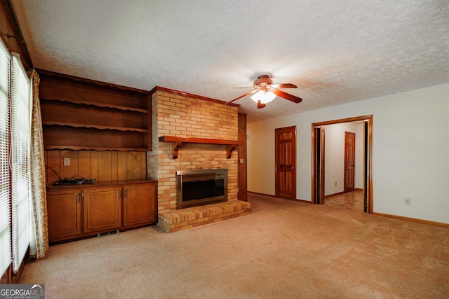 unfurnished living room with ceiling fan, a fireplace, a textured ceiling, plenty of natural light, and light colored carpet