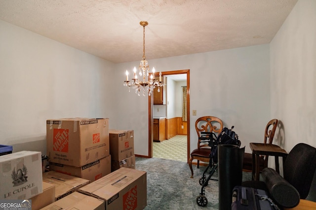 carpeted dining area with a textured ceiling and a notable chandelier