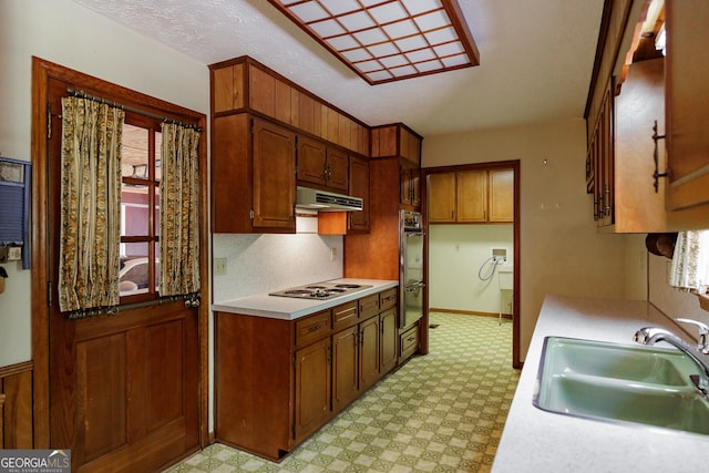 kitchen with black double oven, white gas cooktop, and sink