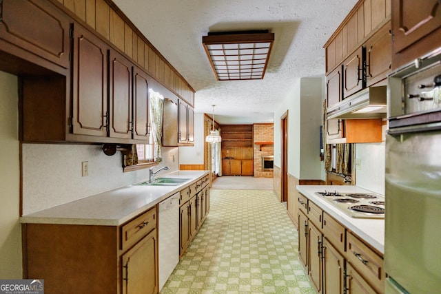 kitchen featuring wood walls, white appliances, sink, hanging light fixtures, and a textured ceiling