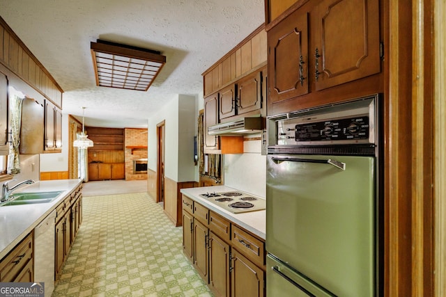 kitchen with wood walls, white appliances, sink, and hanging light fixtures