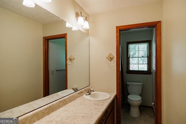 bathroom with tile patterned floors, vanity, a textured ceiling, and toilet