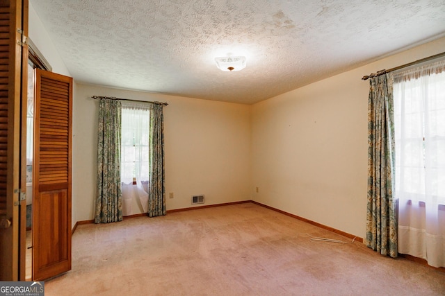 carpeted spare room featuring a textured ceiling