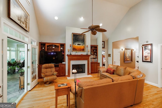 living room with light hardwood / wood-style floors, high vaulted ceiling, and ceiling fan